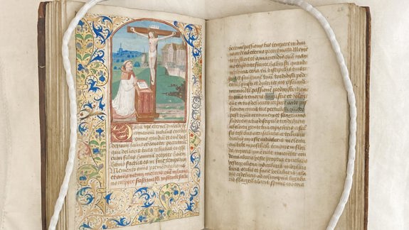 The Blackadder Prayerbook. It is handwritten and on the left page is a painting of Jesus on the cross and someone praying below him.
