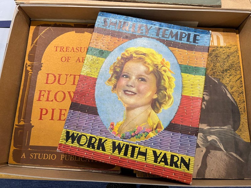 Photo of a box filled with items, including a colourful box with Shirley Temple's face on it and the words read "Shirley Temple Work With Yarn".