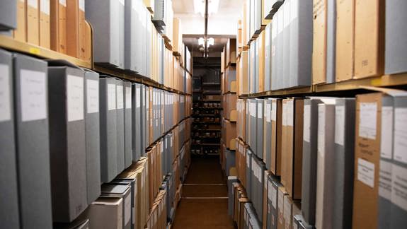 Two rows of shelves lined with archival folders.