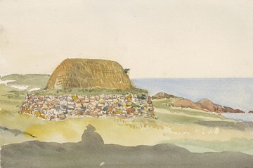 A small thatched house surrounded by rocks facing the sea