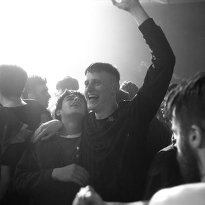 A film still of two people celebrating on a crowded dancefloor.