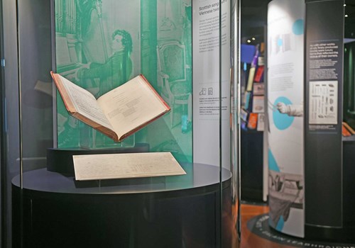 A photo of the Treasures exhibition showing an open book in a display case.