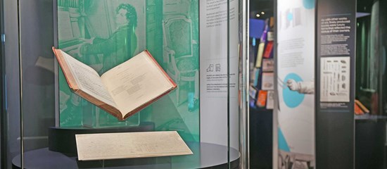 A photo of the Treasures exhibition showing an open book in a display case.