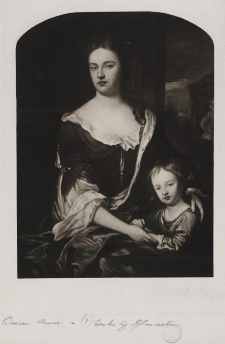 A women sitting with a young child by her side. Both are facing the viewer.