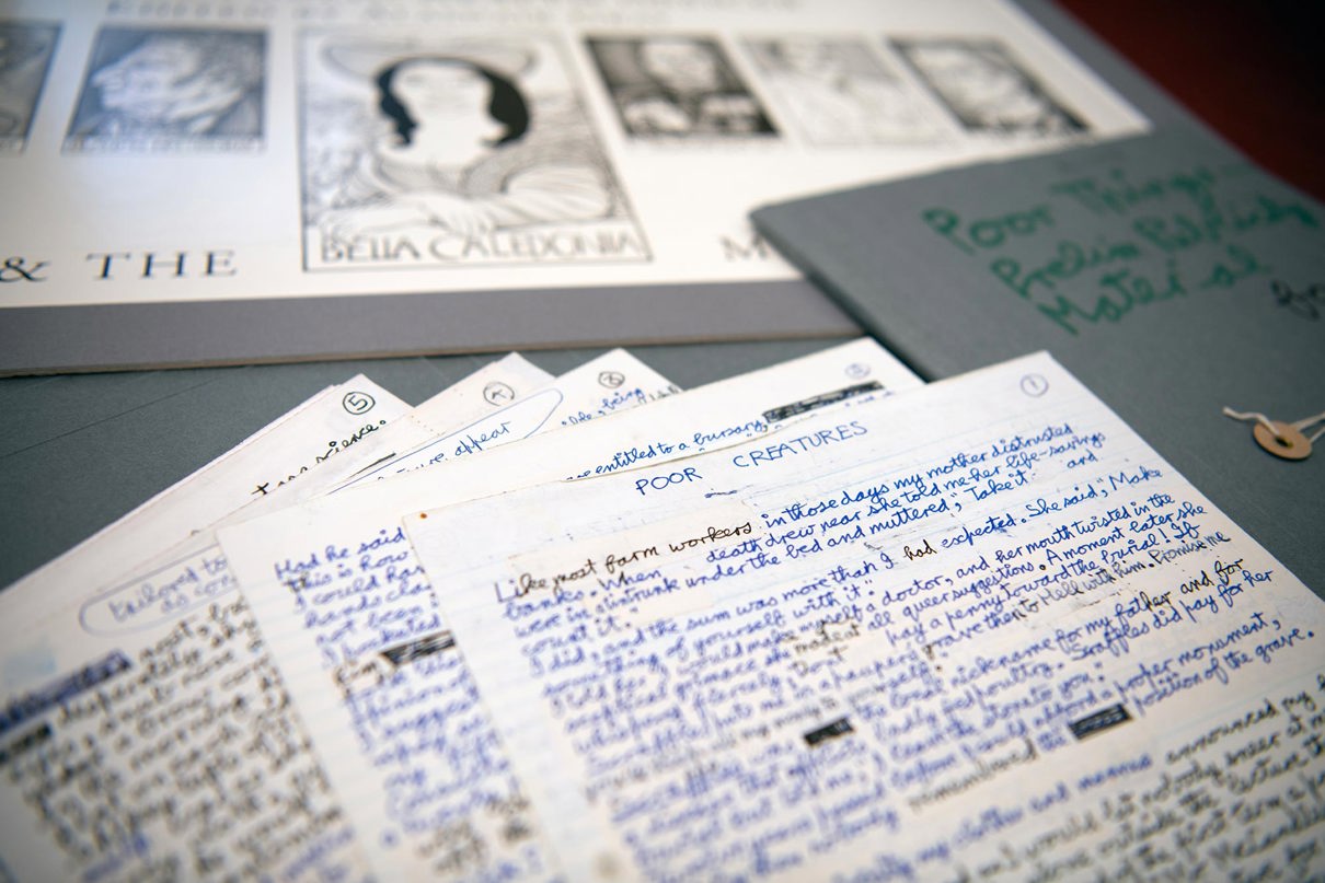 Handwritten drafts of 'Poor things' spread out. In the background is a black and white illustration titled 'Bella Caledonia'.