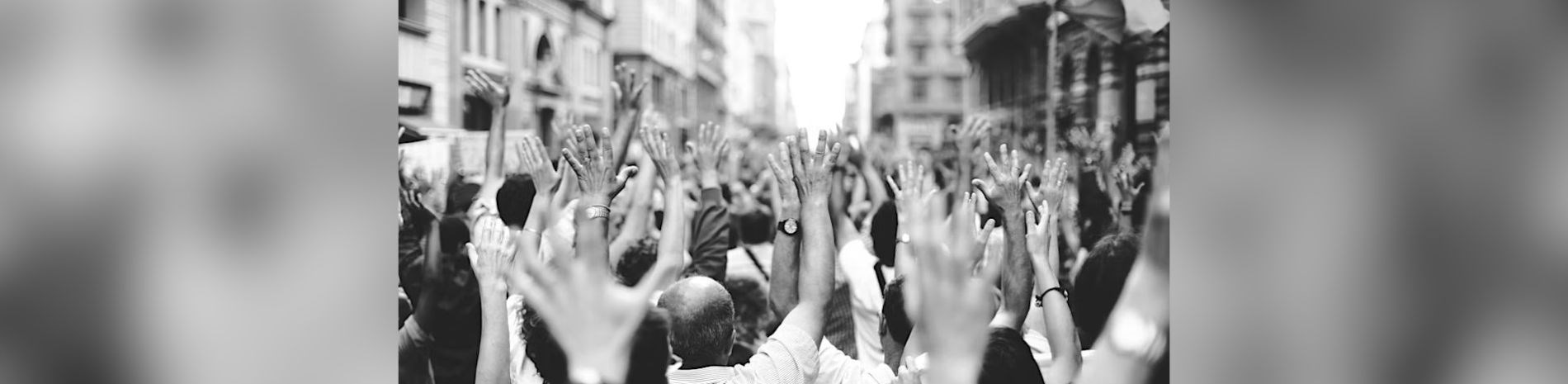 A black and white photo of a crowd with their hands up.