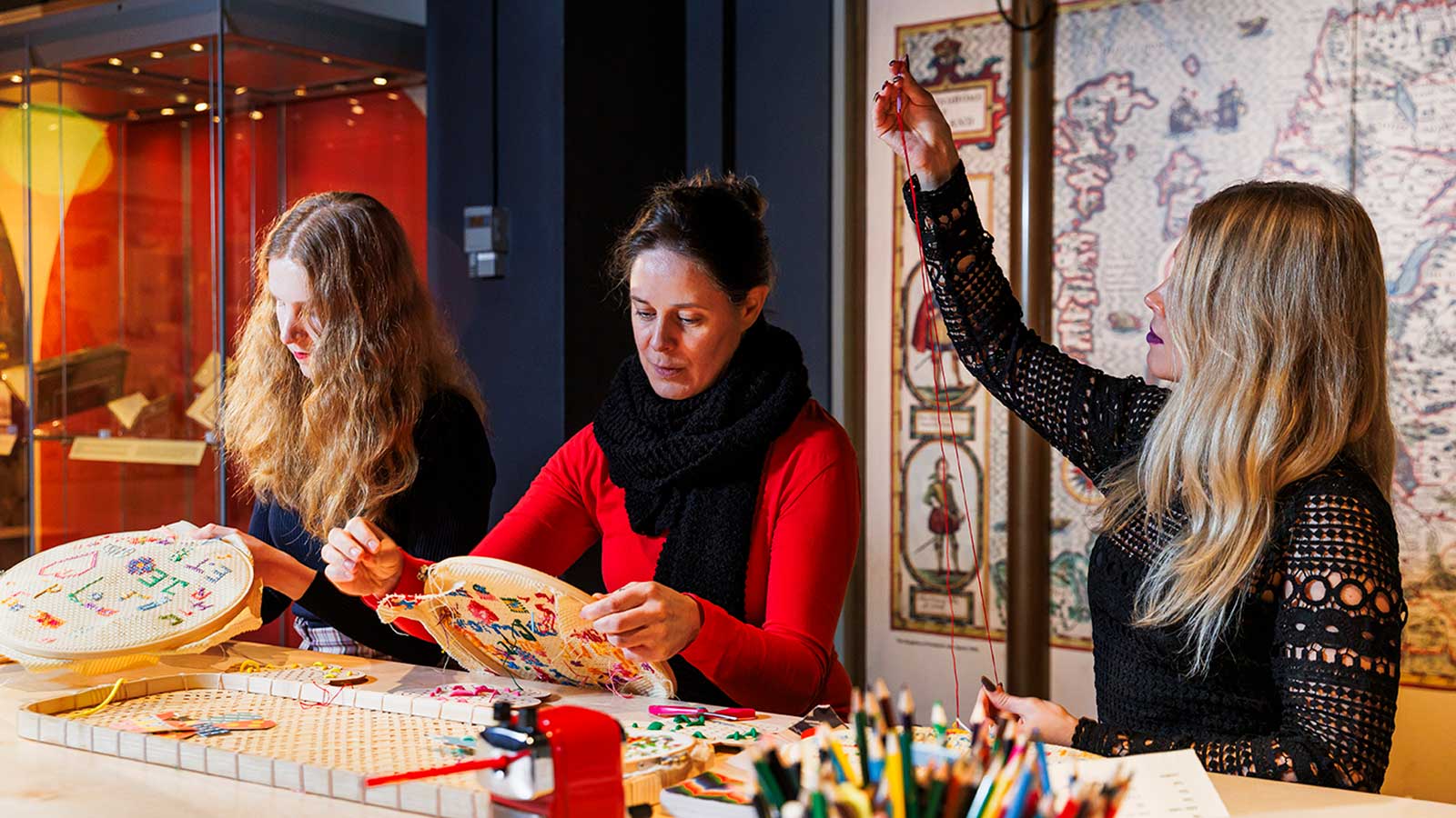 People cross-stitching in a craft workshop