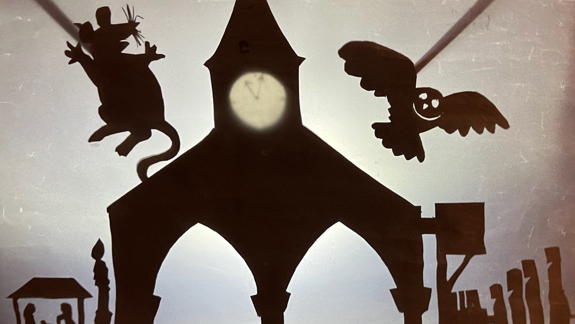 Shadow puppets of a mouse and an owl next to a clock tower.