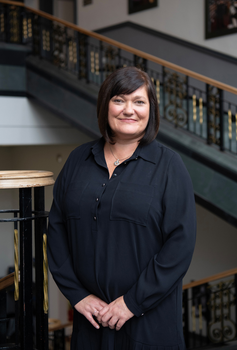 Portrait photo of Anne Boyle standing on the main staircase in the Library.