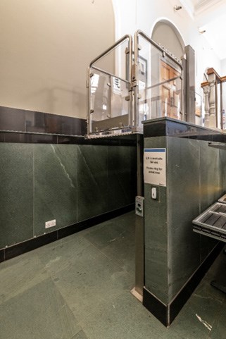 Interior photo of an accessible glass lift next to steps.