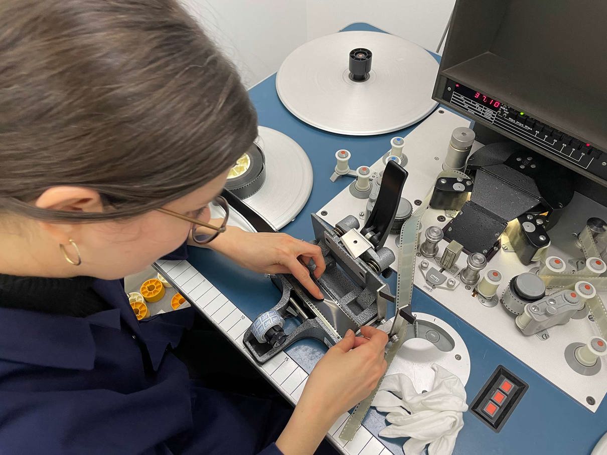 Photo of a woman working on the film strips using specialist equipment.