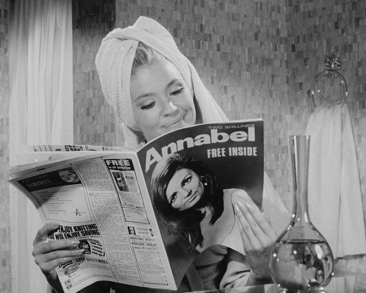 Black and white photo of a woman reading Annabel with a towel wrapped rounder her wet hair.