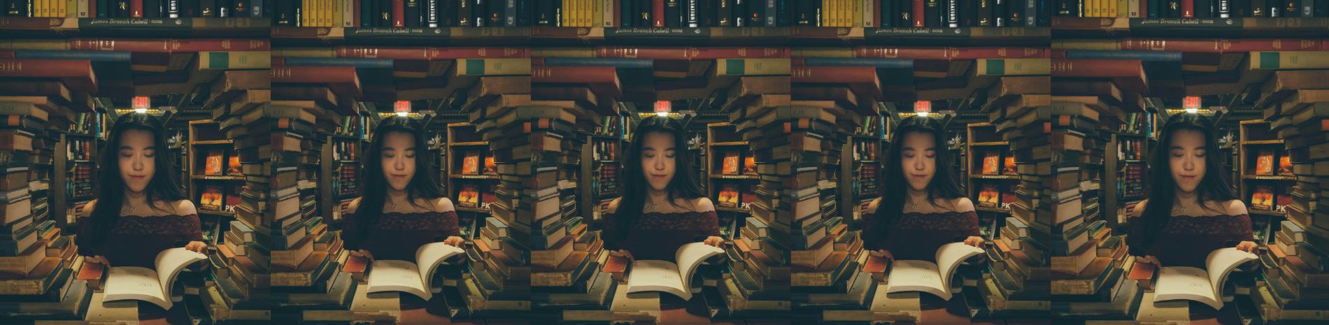 A woman looks through a circle-shaped gap in a wall of books.
