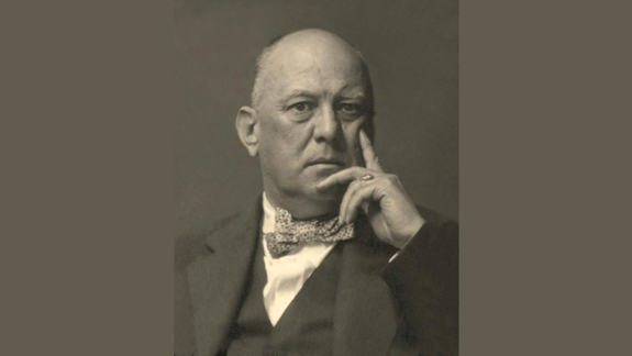 A man looking at the camera with his hand on his face as though he is thinking.