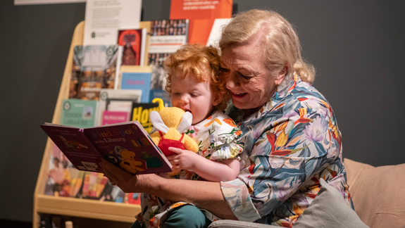 A child sitting on an adult's lap being read to.