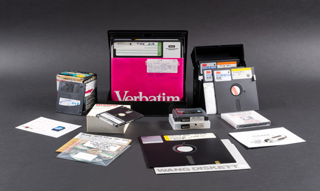 A collection of older technology including floppy disks, SD cards, and CD-ROMs.