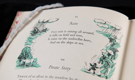 A poem called 'Rain' by Robert Louis Stevenson, surrounded by an illustration showing rain and people with umbrellas.