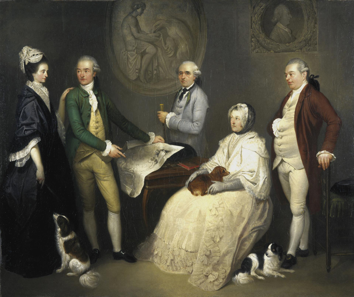 A formal eighteenth‑century group portrait showing five people gathered around a table with a large map, with small dogs in the foreground and classical artworks on the wall behind.