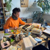 A man at a typewriter on a table in an eclectic studio.
