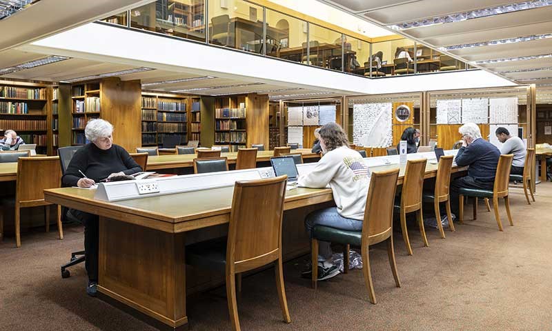People studying at a long desk in a library