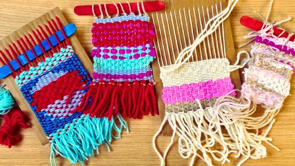 Cardboard weaving looms with stripes of coloured yarn.