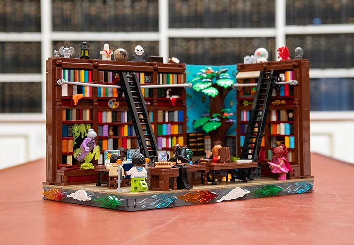 A library with people in it and walls of bookshelves made out of Lego pieces