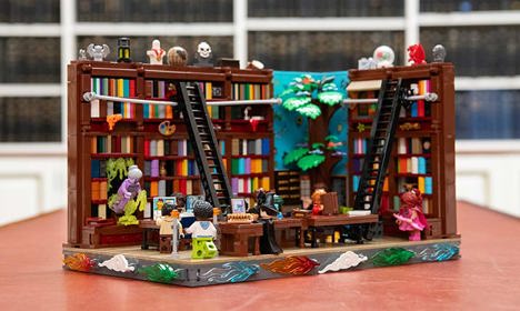 A library with people in it and walls of bookshelves made out of Lego pieces