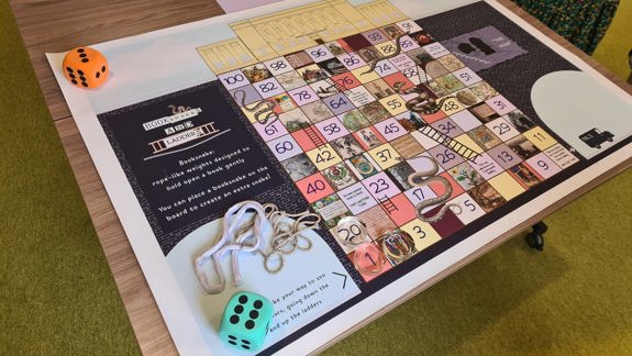A large Library-themed snakes and ladders gameboard.
