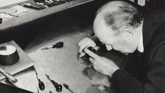 A black and white photo of a man engraving copperplate.
