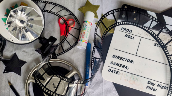 Directors board, film rolls and scissors decorate a table.