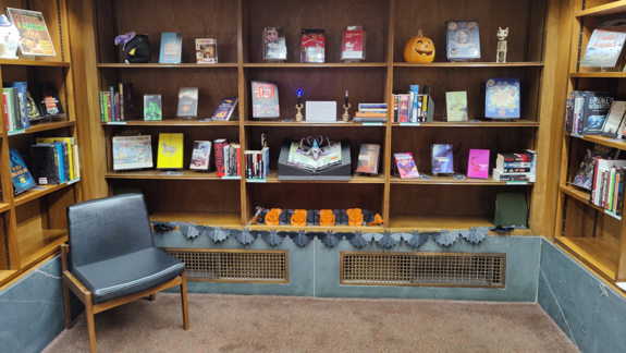 A bookshelf full of books and Halloween-themed decorations.
