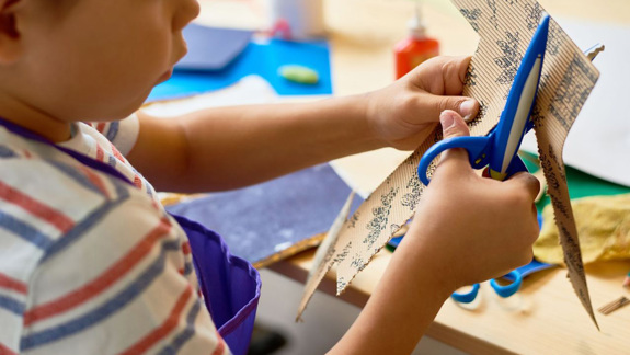 A child cutting patterned cardboard.