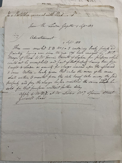 A handwritten notice on aged paper, titled “Advertisement,” detailing information about three cases of books, prints, and paintings, with neat cursive script across the page.