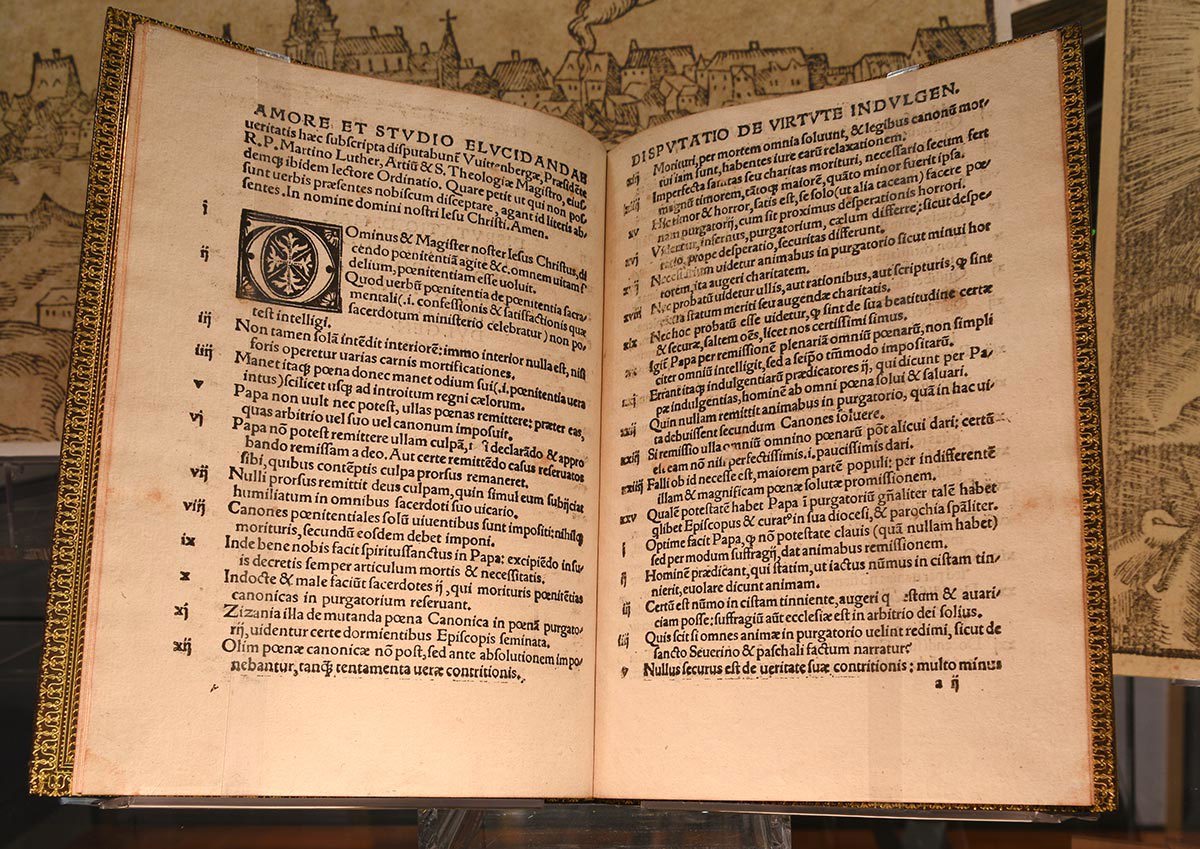 An open book displaying two pages of Latin text. Both pages are structured with numbered sections and feature decorative borders. The left page includes an ornate initial letter.