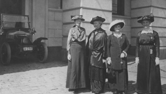 A black and white photo of four women in old dress and hats.