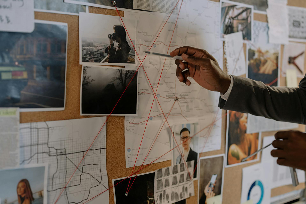 A pin board with maps, photos, and notes on it.