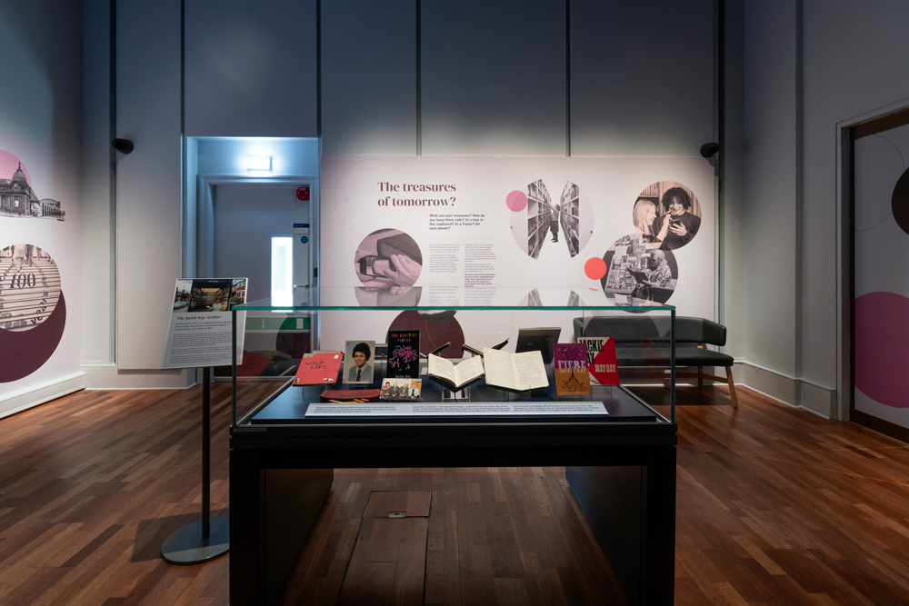 In the foreground, a display case showing Jackie Kay ephemera and in the background an exhibition panel asking "The treasures of tomorrow?".