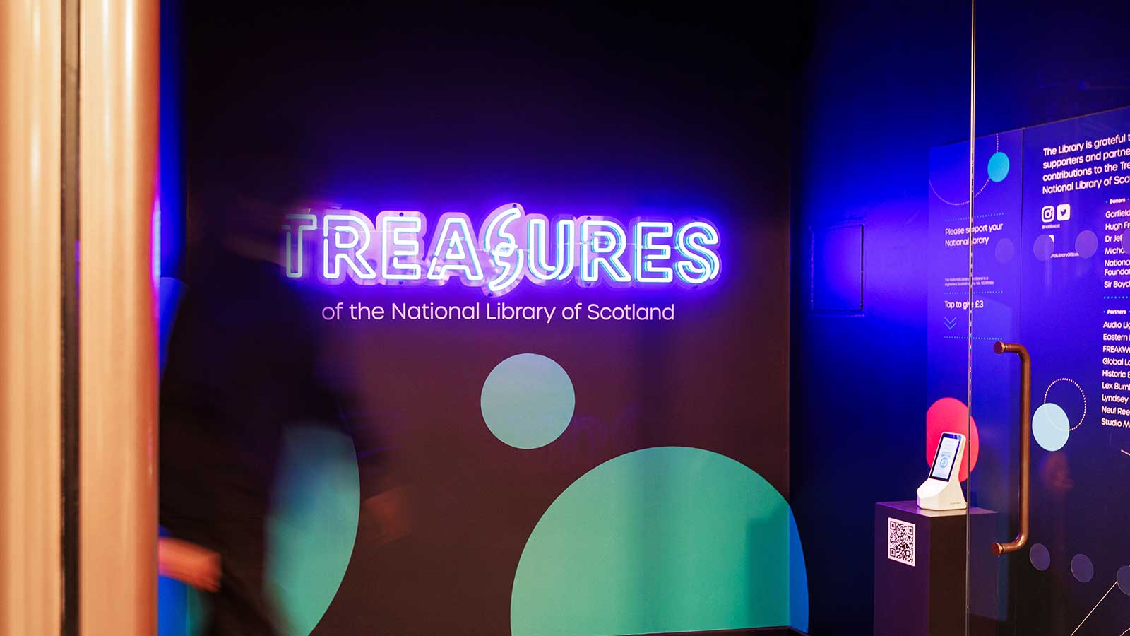 A neon sign saying 'Treasures' at the entrance to an exhibition