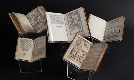 Five old books on display showing early depictions of witches.