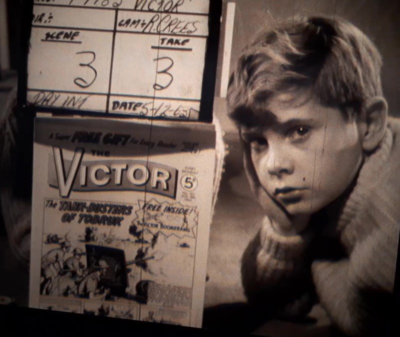 Grainy sepia toned still from an ad of a young boy sitting next to a Victor magazine.