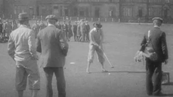People on a golf course watching as someone gets ready to hit the ball with a golf club