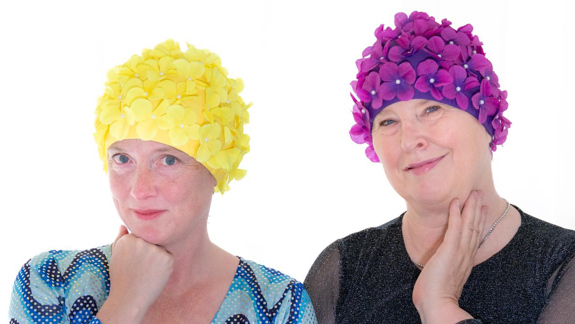 Jackie Kemp and Vicky Allan dressed in swimming caps covered in flowers.