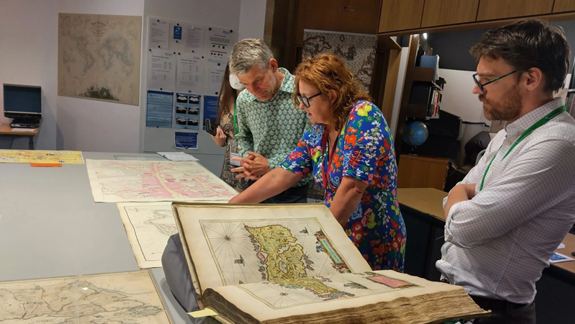 Three people looking at maps.