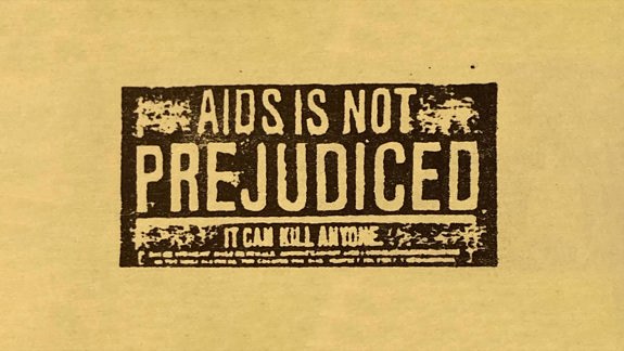 Sepia paper with a black stamp on it that reads "AIDS is not prejudiced, it can kill anyone".