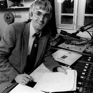 Person sitting at desk with soundboard and holding paper.