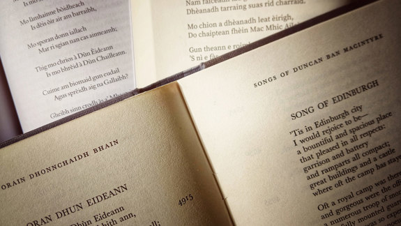 A pile of open books with songs in Gaelic and English.