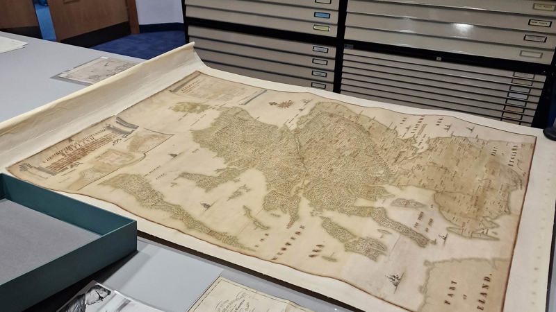 A map of Scotland laid out on a table with a plan chest behind it.