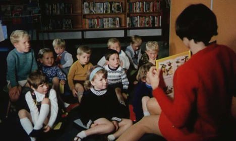 Children sitting in a library listening to a story being read to them