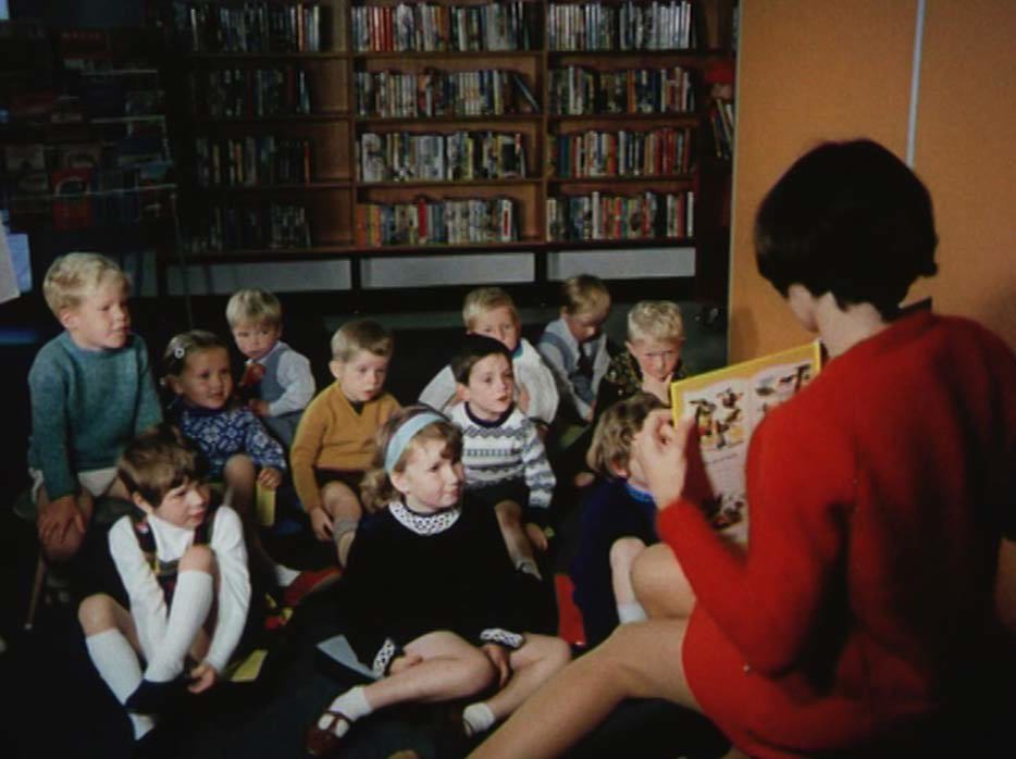Children sitting in a library listening to a story being read to them