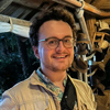 Head and shoulders of a man with curly hair and glasses.